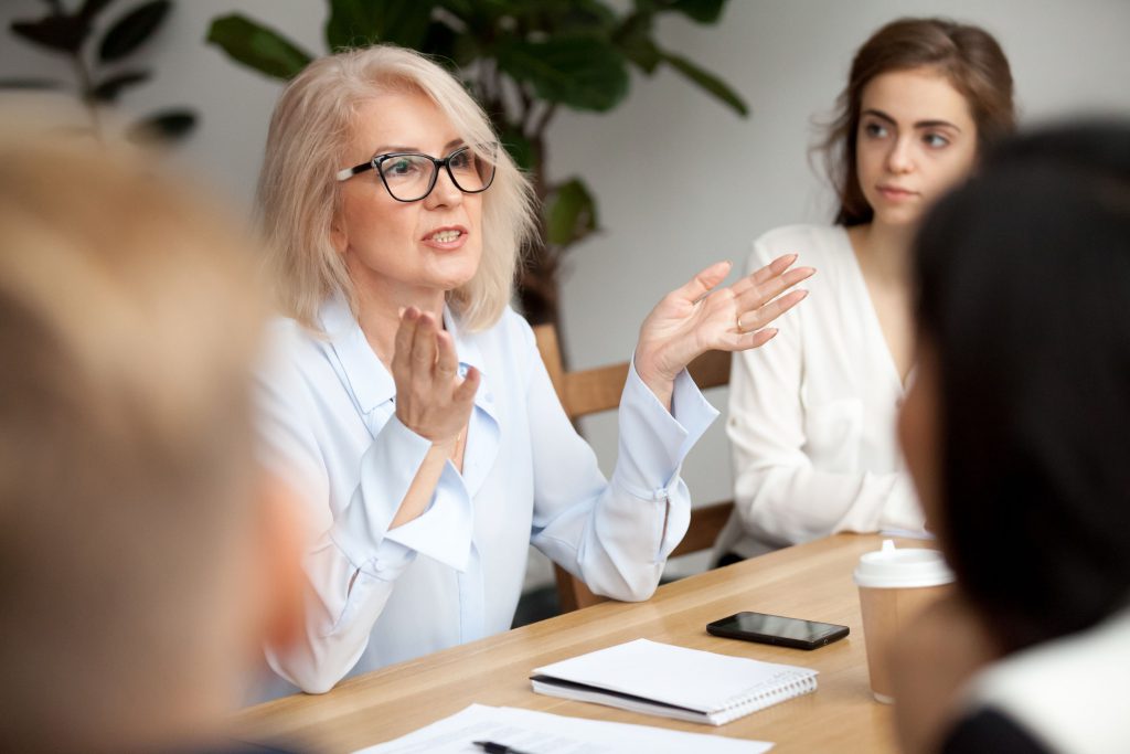 Aged businesswoman, teacher or business coach speaking to young